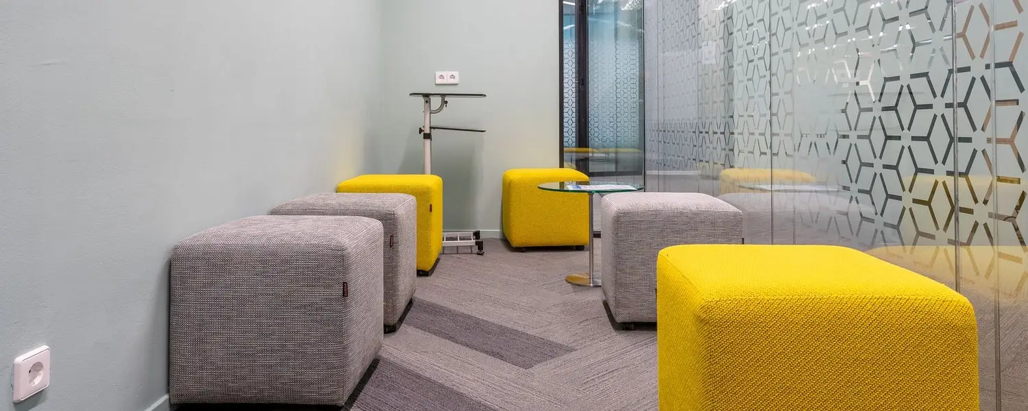 Customer waiting area with seating, a glass partition wall and clean carpet tiles