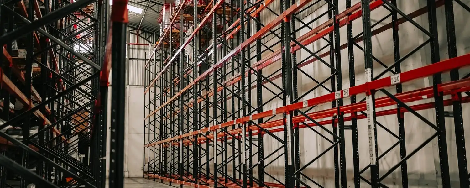 Wide aisle between empty pallet racking in a warehouse with a swept concrete floor